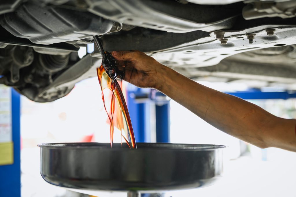 Mechanic draining engine oil during a car service